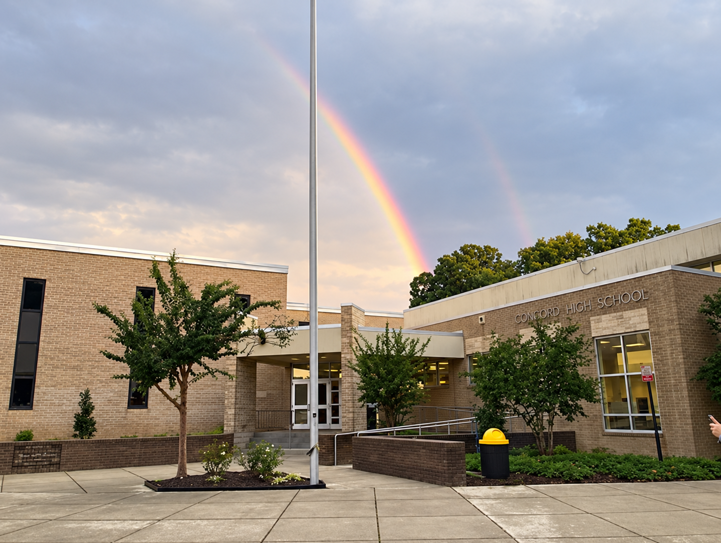 Concord High School entrance and courtyard beneath a rainbow, where New Healing Place meets on Sundays